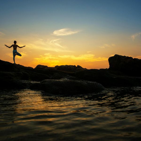 Silhouette of a person in a warrior yoga pose against a beautiful sunset.